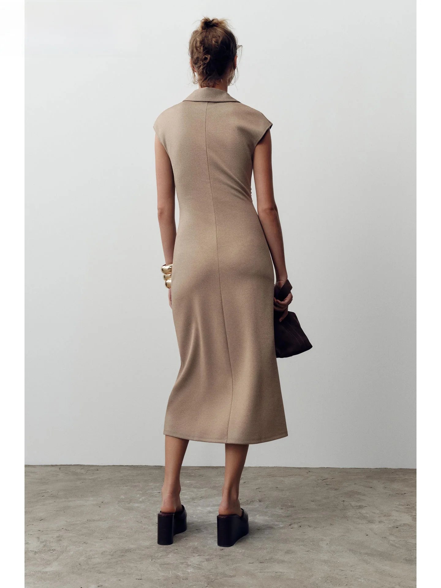 Woman wearing a beige dress against a plain background