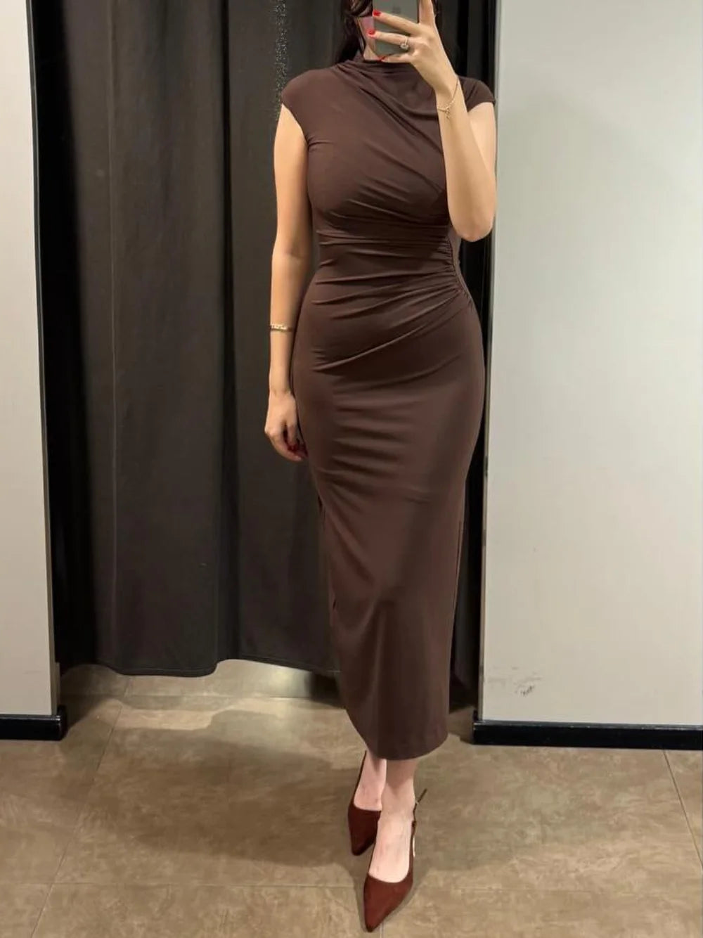 Person wearing a brown dress standing in front of a mirror.